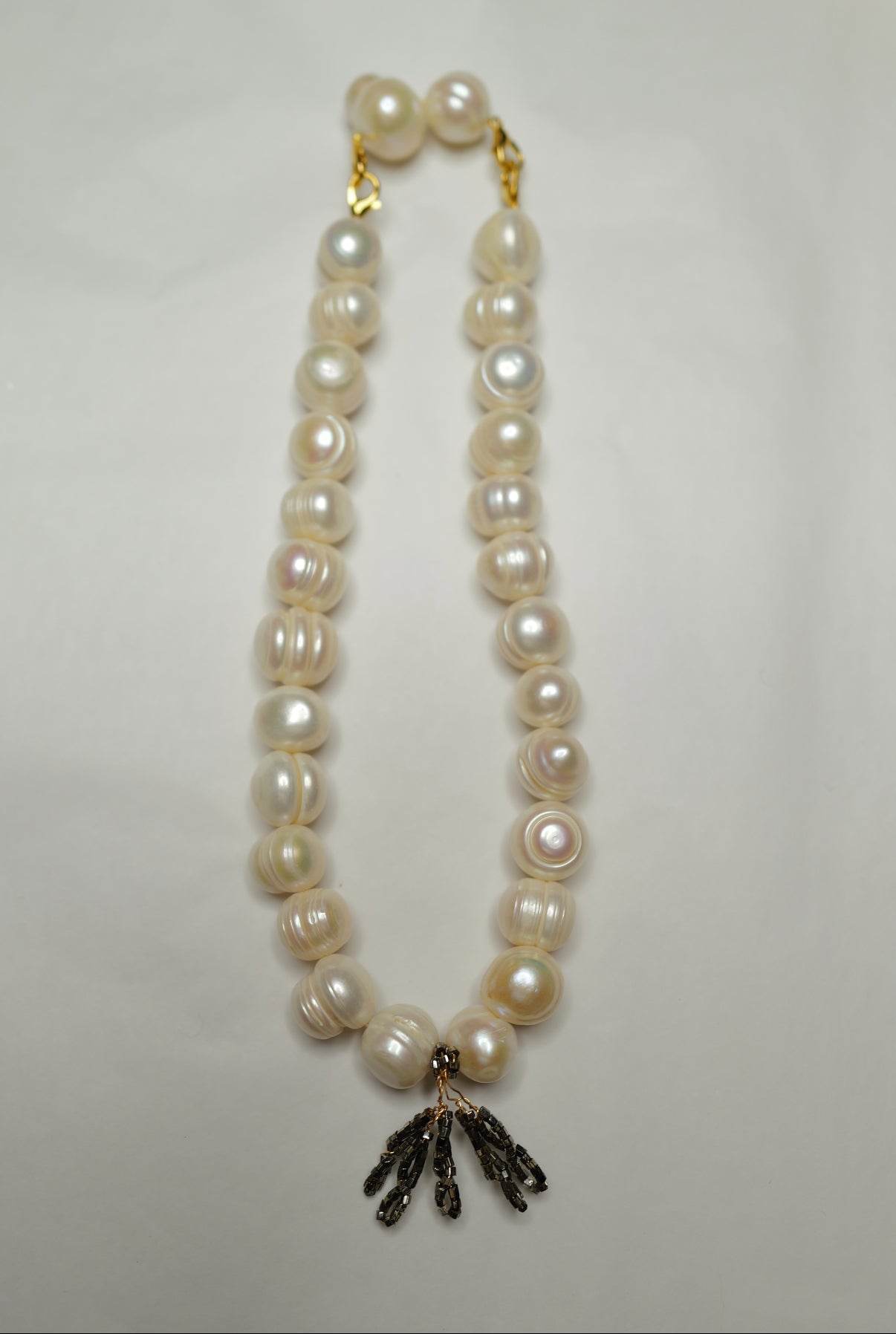 Pearl necklace with a gold clasp on a light gray background