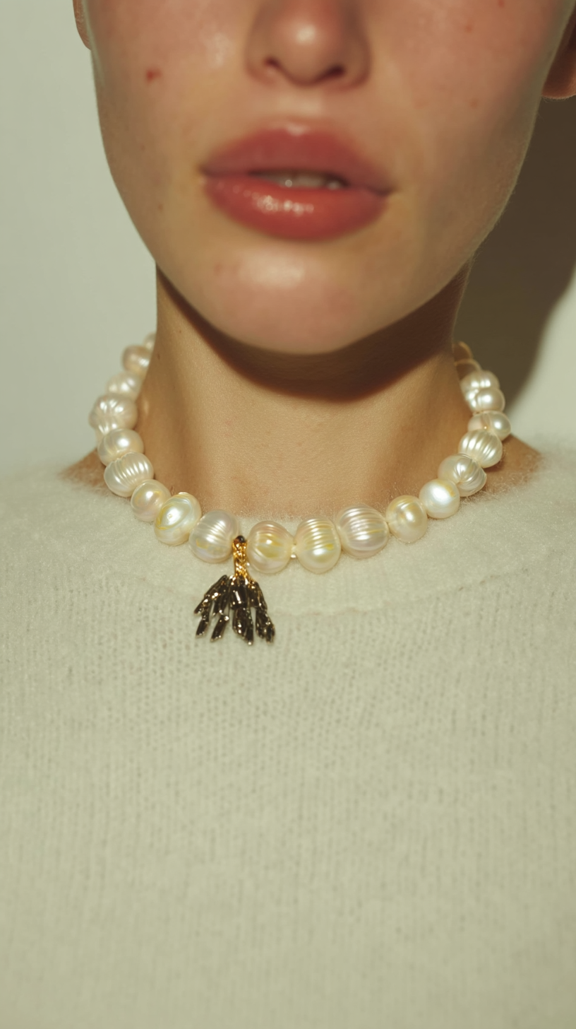 Pearl necklace with a pendant worn by a person on a light background